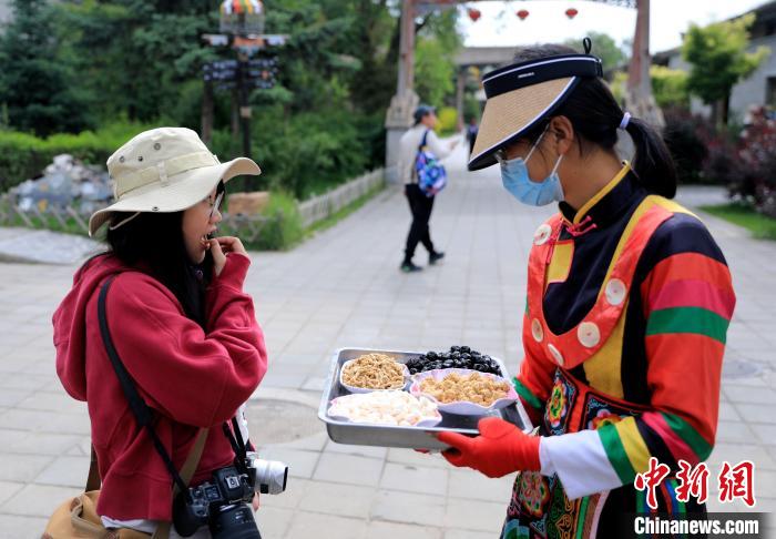 圖為身穿土族服飾的女性介紹當?shù)靥厣〕?。　薛?攝